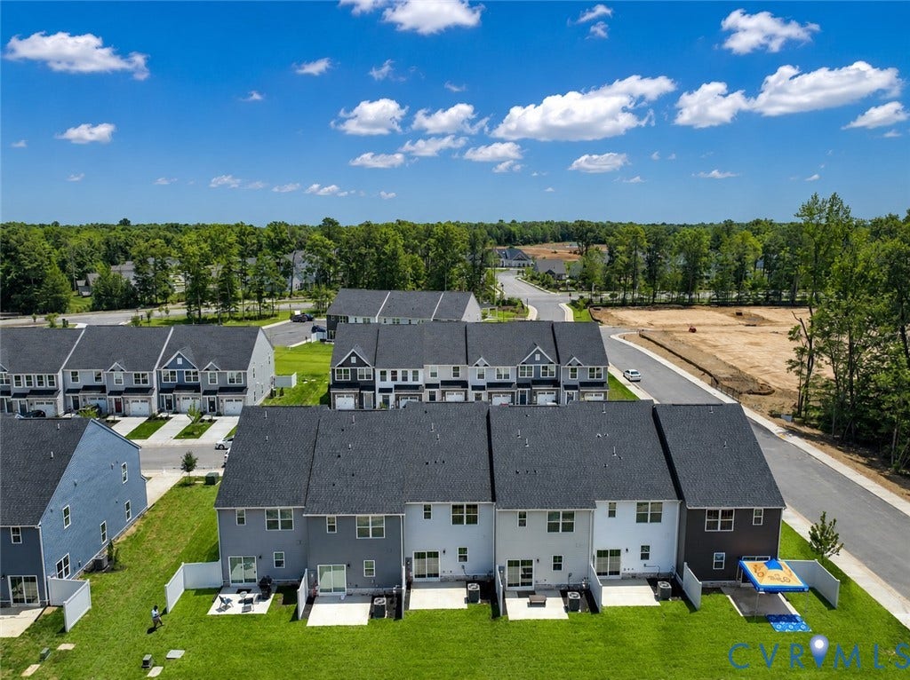 10607 Pink Lilly Lane, Chester, VA 23831 Aerial perspective showcasing multiple townhomes with private fenced yards, individual patios, and lush green lawns