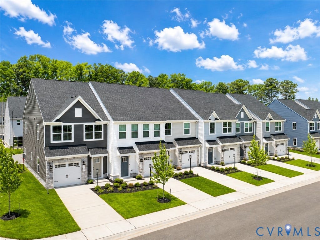 10607 Pink Lilly Lane, Chester, VA 23831 Row of townhomes featuring varied siding finishes, attached garages, and manicured landscaping