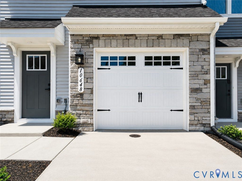 10607 Pink Lilly Lane, Chester, VA 23831 White garage door with decorative hardware, stone veneer facade, and concrete driveway