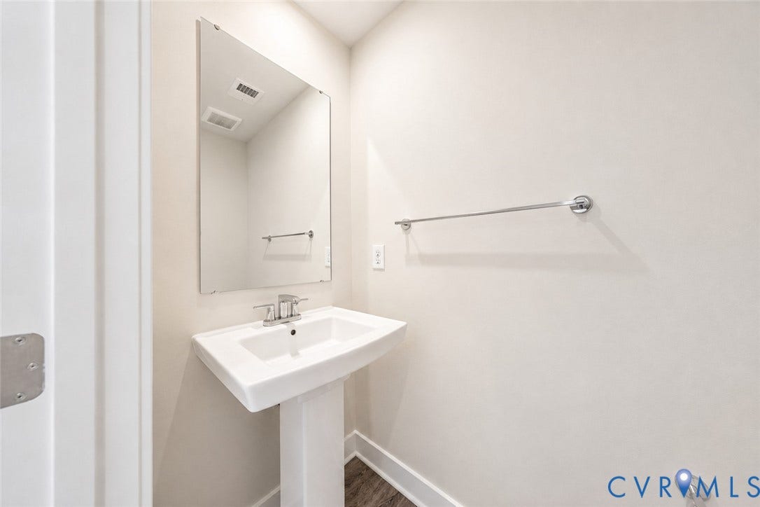 10607 Pink Lilly Lane, Chester, VA 23831 Pedestal sink with chrome faucet, large wall-mounted mirror, and wood-finish flooring