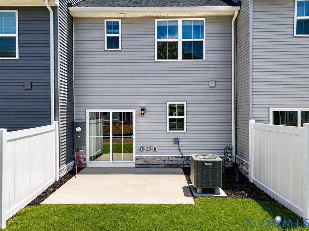 10607 Pink Lilly Lane, Chester, VA 23831 Rear exterior with light gray siding, white vinyl fencing, a concrete patio, and a sliding glass door
