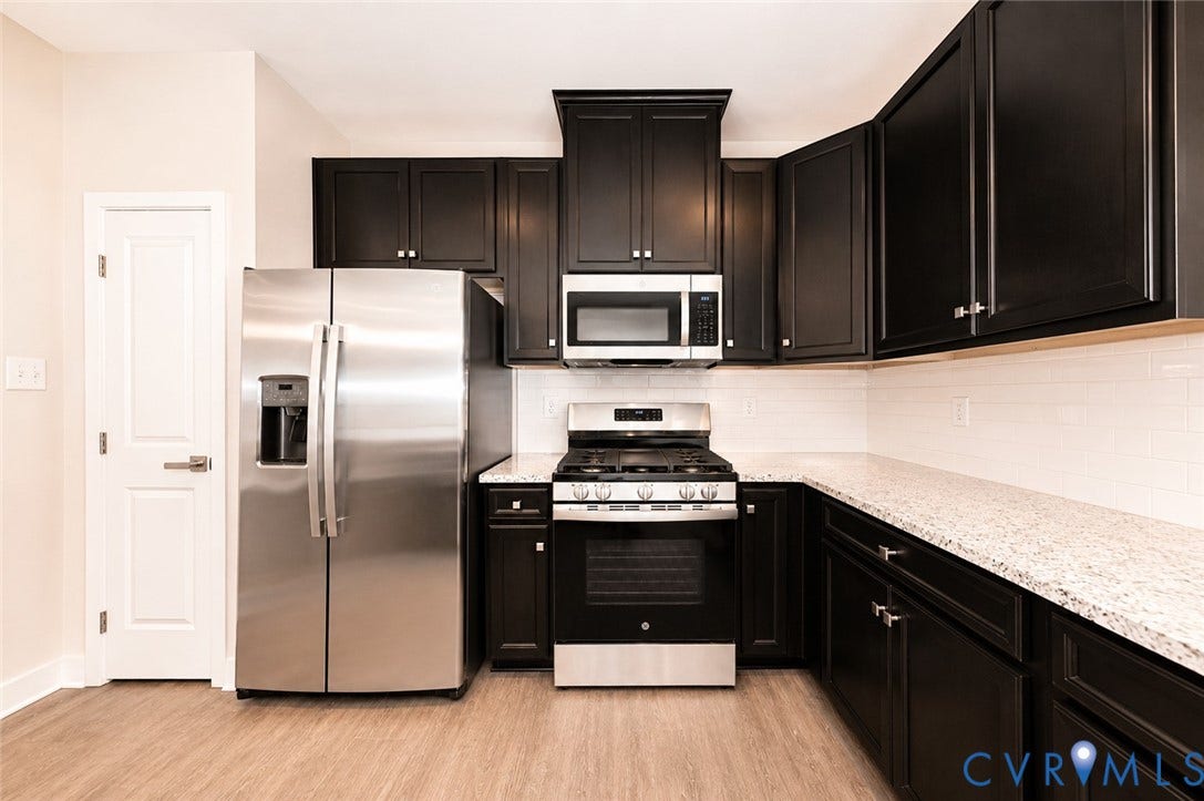 10607 Pink Lilly Lane, Chester, VA 23831 Kitchen featuring dark cabinetry, stainless steel appliances, light-toned countertops, white subway tile backsplash, and wood-finish flooring