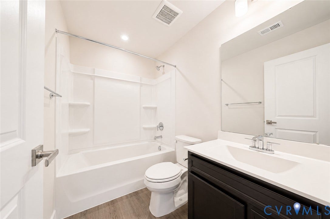 10607 Pink Lilly Lane, Chester, VA 23831 Bathroom featuring a white tub/shower combination, dark wood-finish vanity, white countertop with integrated sink, and wood-finish flooring