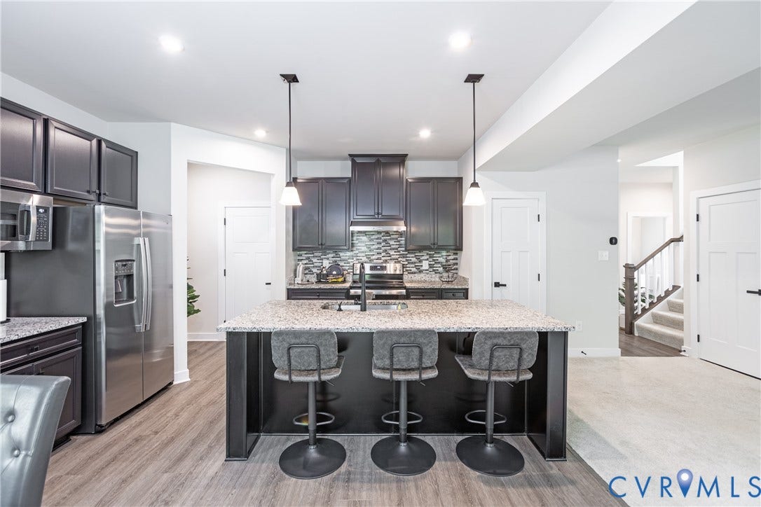 1943 Enon Station Drive, Chester, VA 23836 Kitchen featuring a large island with pendant lighting, stainless steel appliances, dark cabinetry, and wood-finish flooring