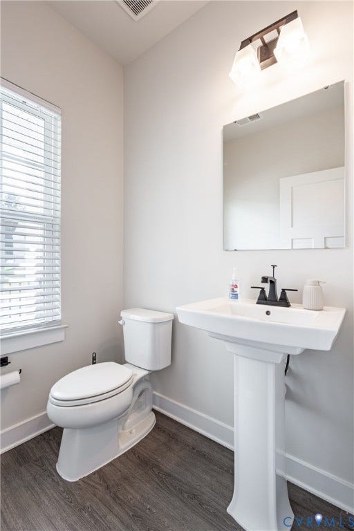 1943 Enon Station Drive, Chester, VA 23836 Bright powder room featuring a pedestal sink with chrome faucet, toilet with elongated bowl, large framed mirror, recessed lighting, and dark wood-finish flooring