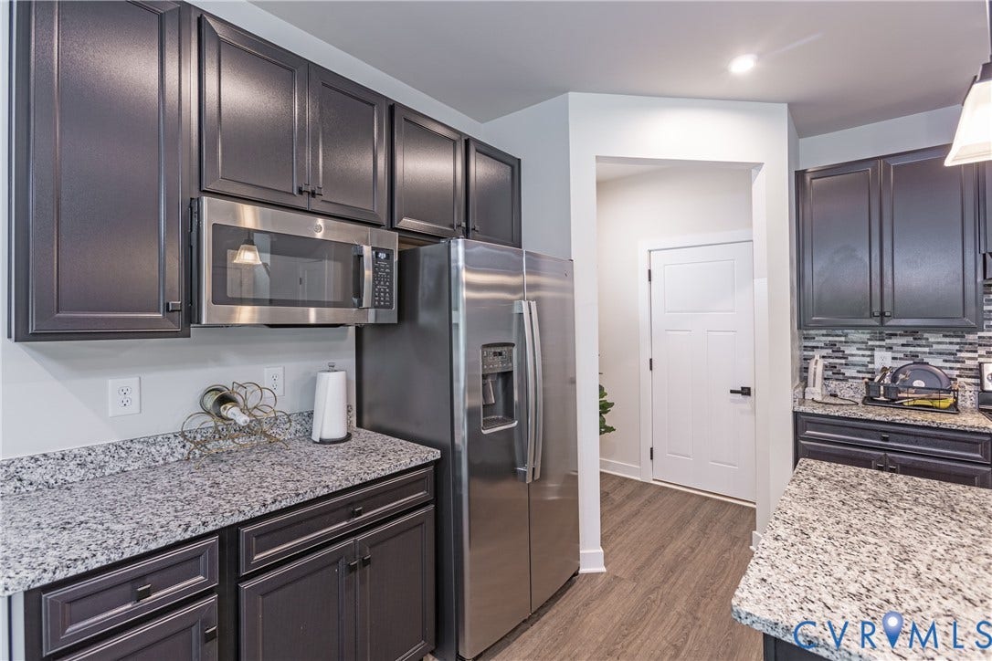 1943 Enon Station Drive, Chester, VA 23836 Stainless steel microwave, stainless steel refrigerator, dark wood-finish cabinetry, granite countertops, and wood-finish flooring