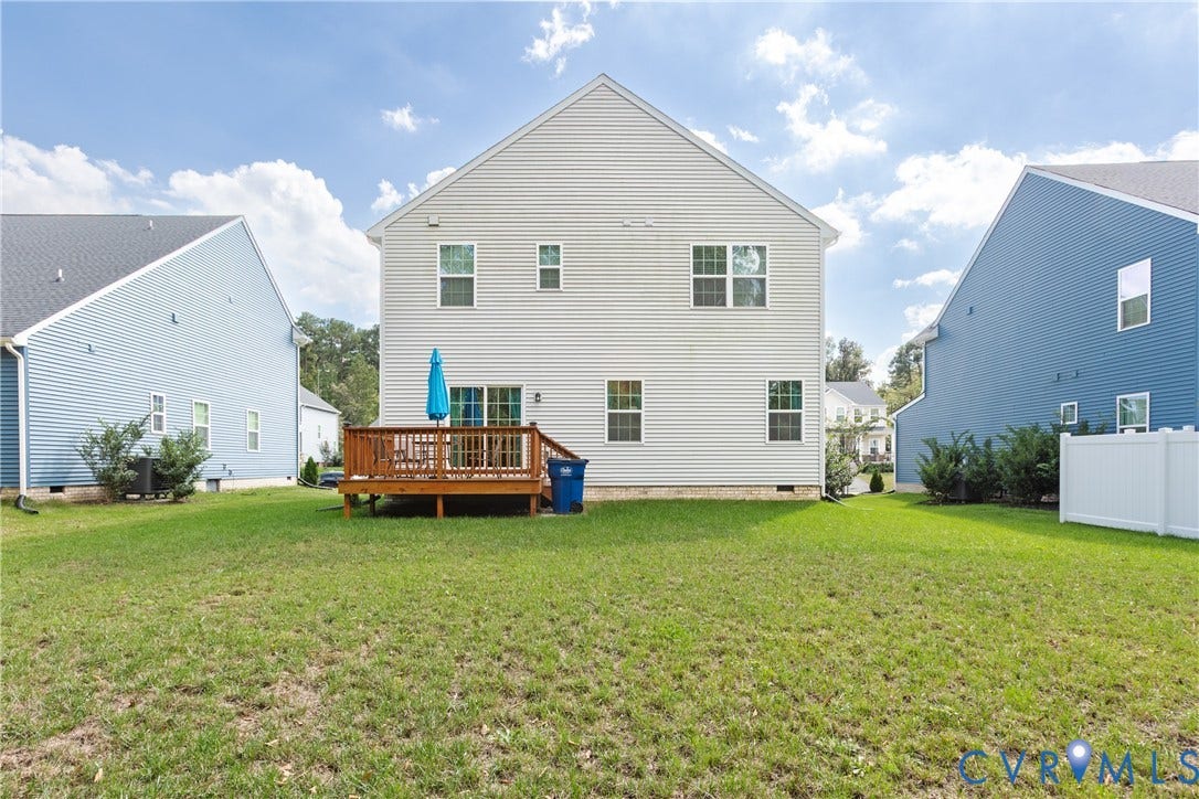 1943 Enon Station Drive, Chester, VA 23836 Rear exterior with light-colored horizontal siding, a ground-level wood deck, and multiple windows