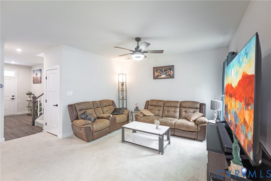 1943 Enon Station Drive, Chester, VA 23836 Living area with light-colored carpeting, a ceiling fan with integrated lighting, and a white interior door