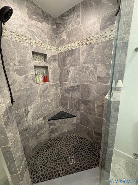 305 N Hamilton Street, #C, Richmond, VA 23221 Shower enclosure featuring gray stone tile walls, a mosaic accent band, built-in recessed shelving, a corner bench, and a river rock shower floor