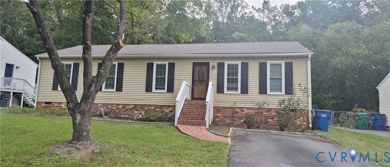 Single-story property with light-colored siding, dark shutters, and a brick foundation