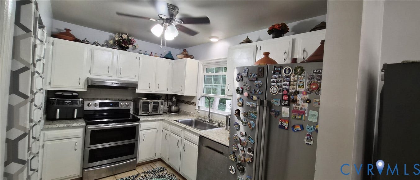 Kitchen featuring white cabinetry, light-toned countertops, stainless steel appliances, and a ceiling fan