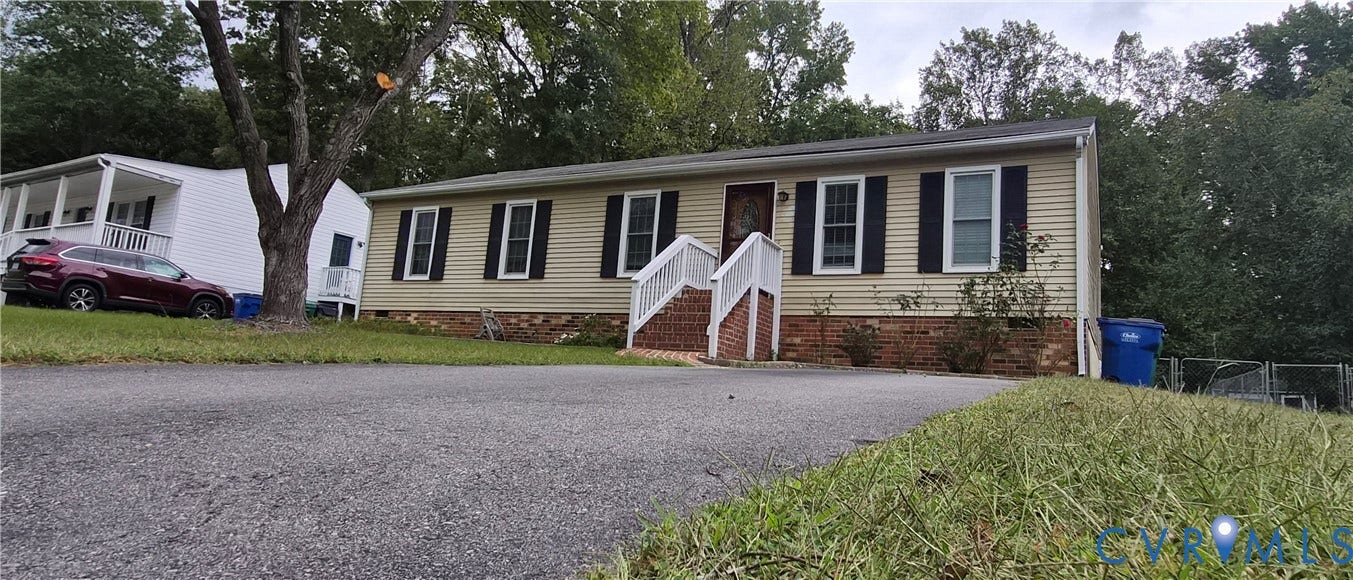 Siding exterior with black shutters, brick foundation, and a white-railed entry porch