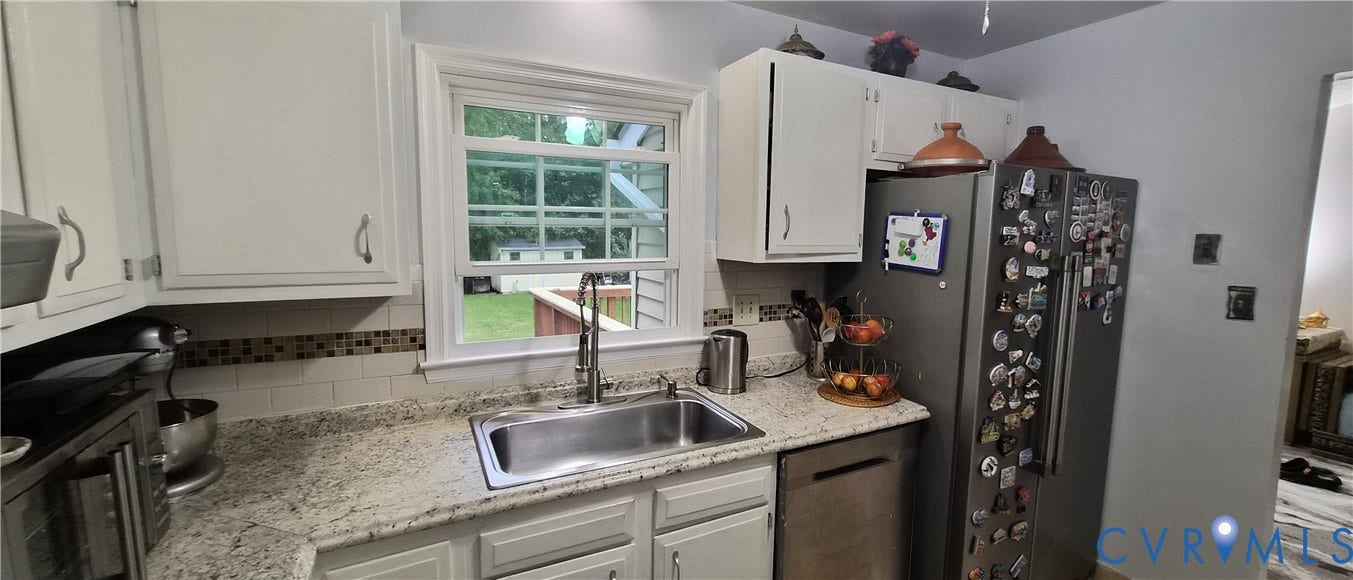 White cabinetry with silver-tone hardware, undermount stainless steel sink, granite-style countertops, and a white subway tile backsplash with mosaic accent