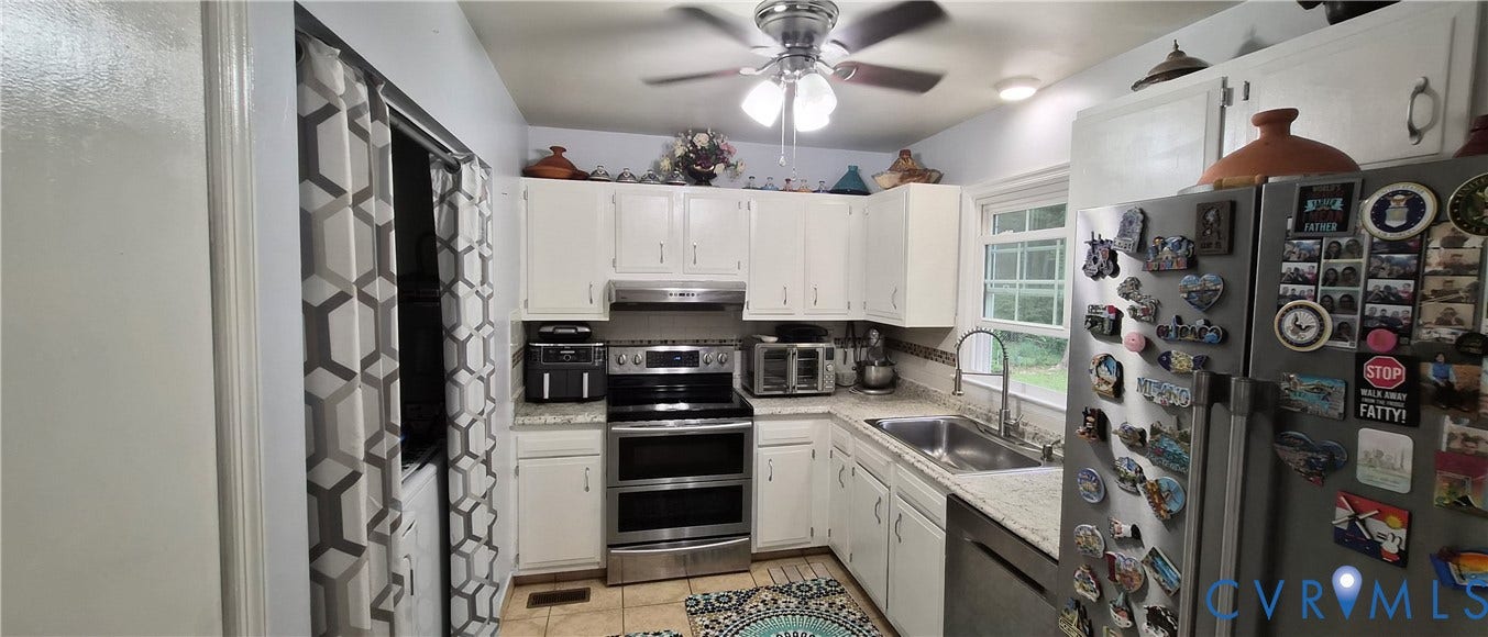 White cabinetry with chrome hardware, stainless steel appliances, granite countertops, tile flooring, and a ceiling fan with integrated lighting