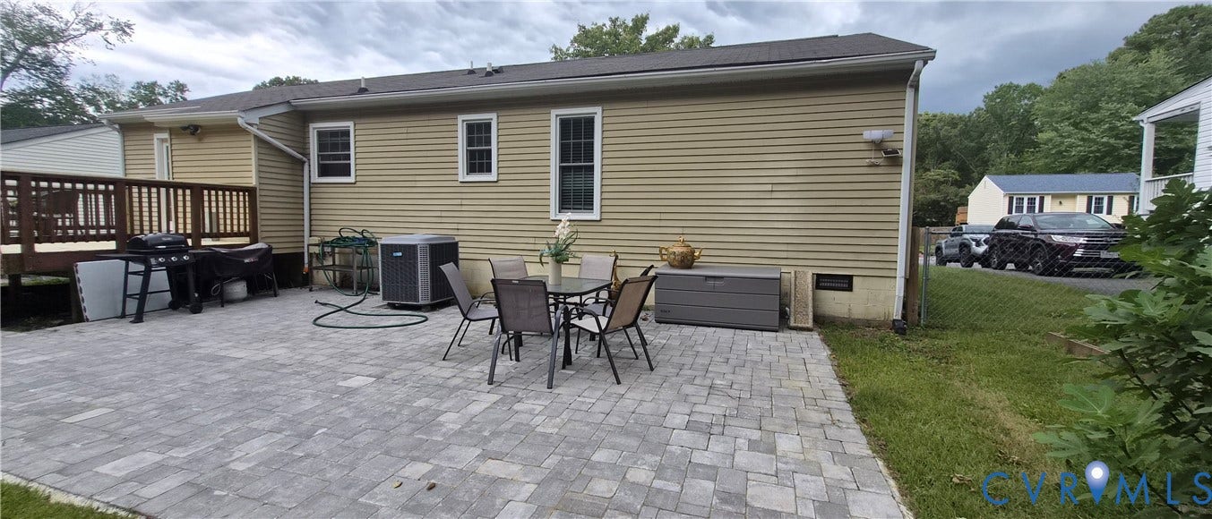 Paver patio featuring a wooden deck and horizontal siding