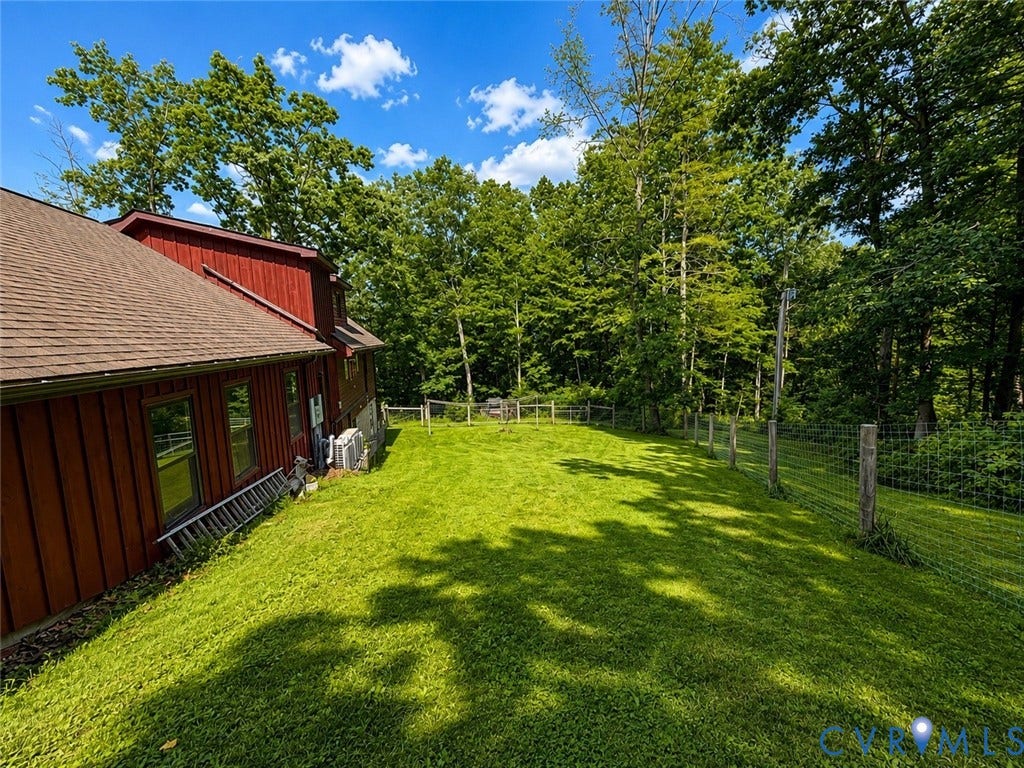 Expansive grassy lawn with a wire fence and mature trees