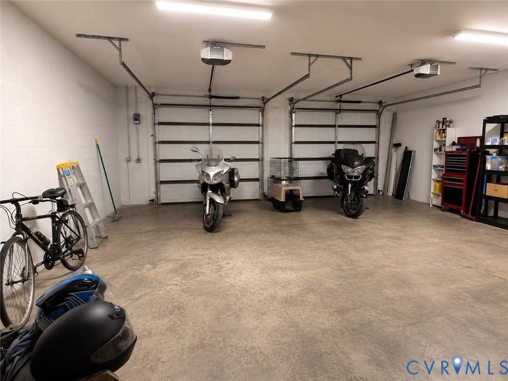 Two-bay garage with automatic door openers, fluorescent ceiling lights, and concrete flooring
