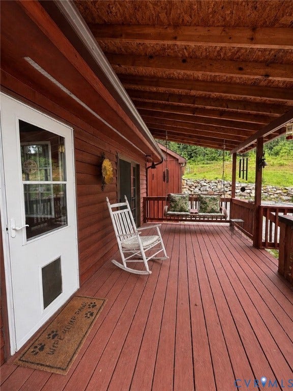 Expansive covered porch with wood-finish decking and exposed beam ceiling