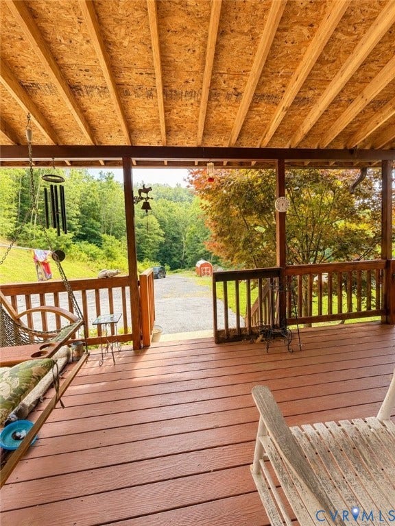 Expansive covered porch featuring wood-finish decking and exposed wood rafters