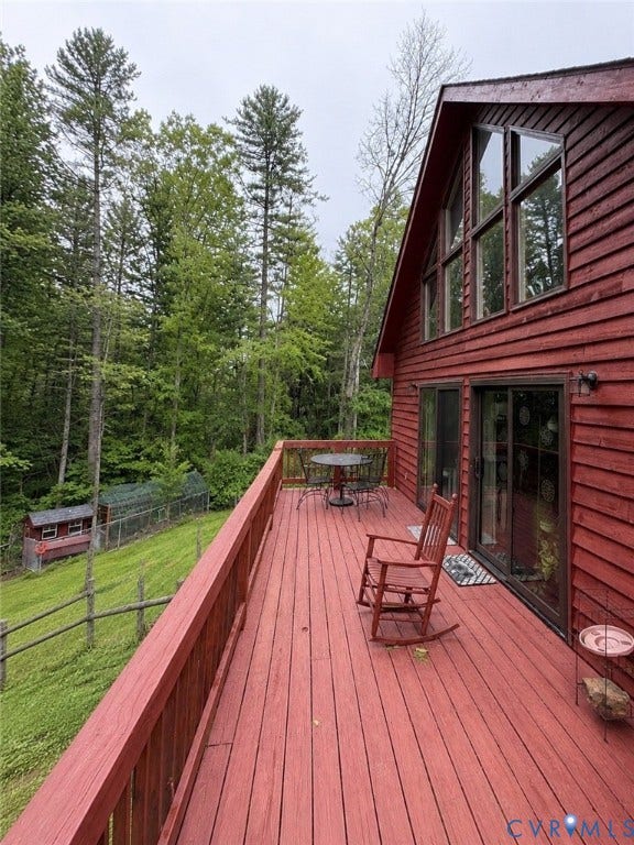 Expansive red-stained wood deck featuring a railing and glass sliding door access