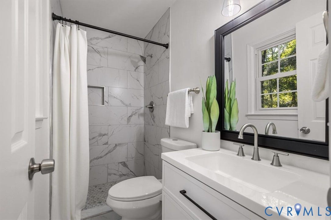 3031 Speeks Drive, Midlothian, VA 23112 Bathroom featuring a white vanity with integrated sink, brushed nickel faucet, large framed mirror, tiled shower with recessed niche, and a window providing natural light