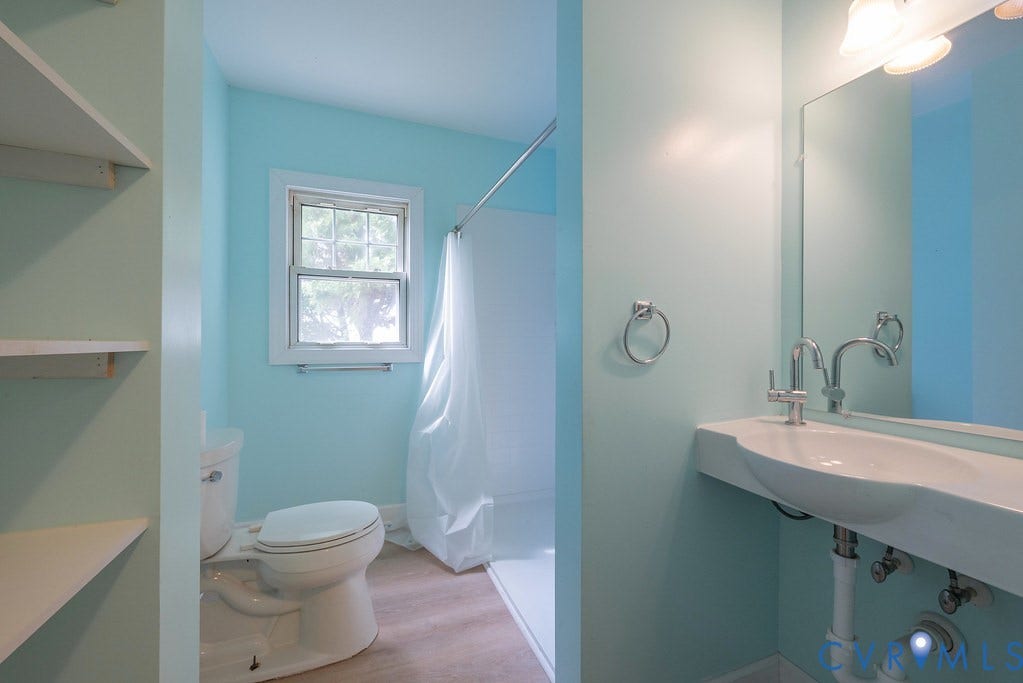 Wall-mounted vanity sink, polished chrome faucet, mirrored wall, and built-in shelving