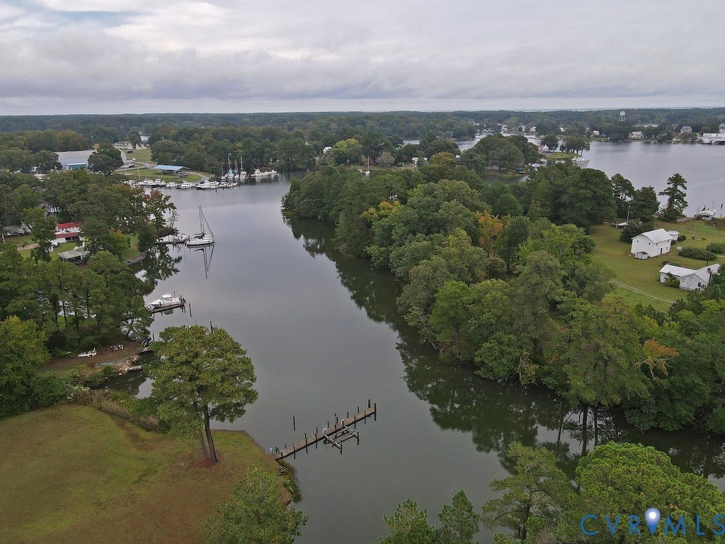 Waterfront property featuring a private pier and mature trees