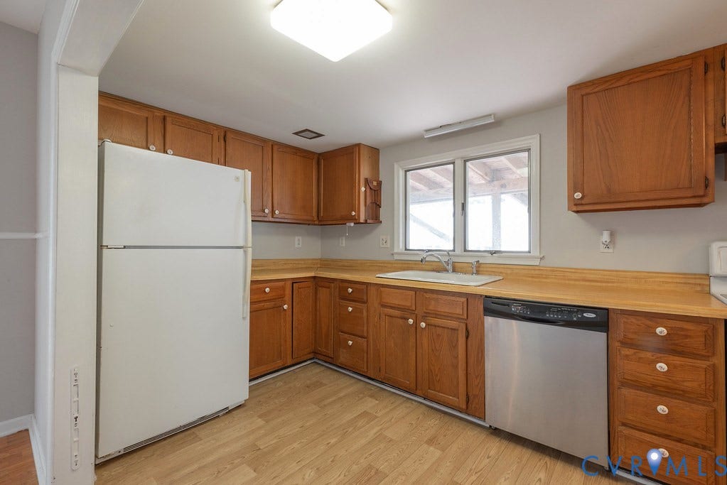 Kitchen featuring wood-finish cabinetry, wood-finish countertops, stainless-steel dishwasher, and a window above the sink