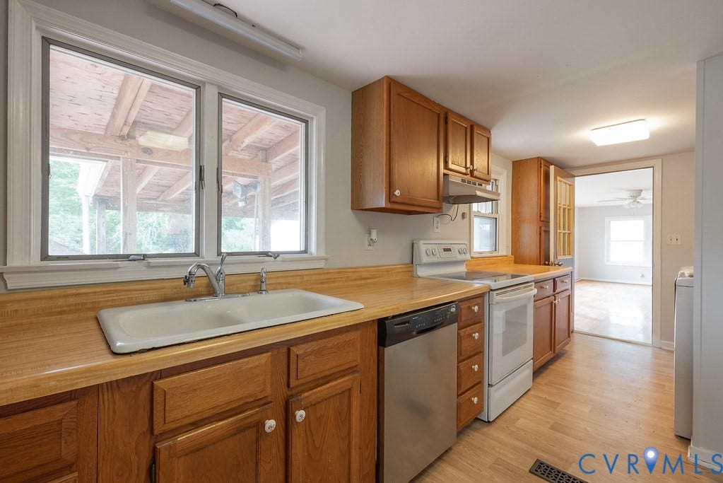 Kitchen featuring wood-finish flooring, wood cabinetry, a double basin sink, and white appliances