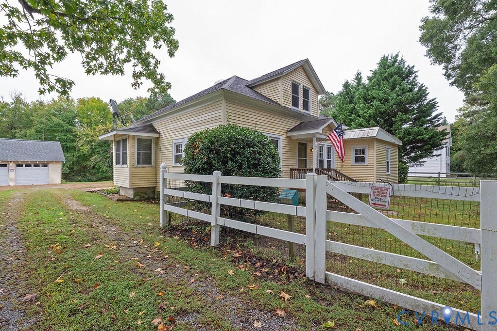 Yellow siding exterior with white trim, a covered front porch, and a two-car detached garage