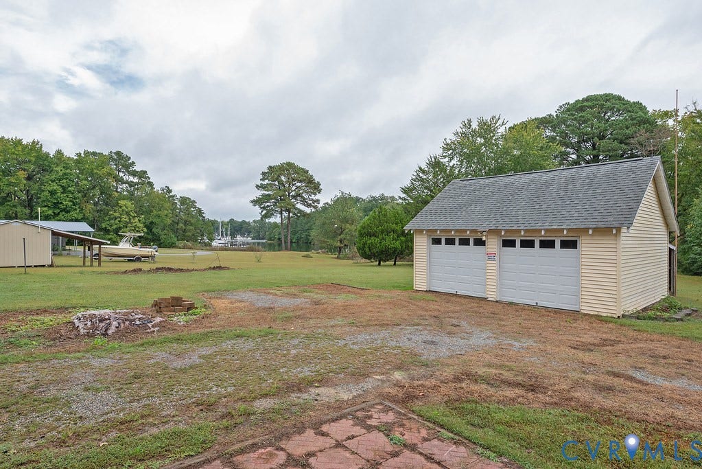 Detached two-car garage with light-colored siding and an asphalt shingle roof