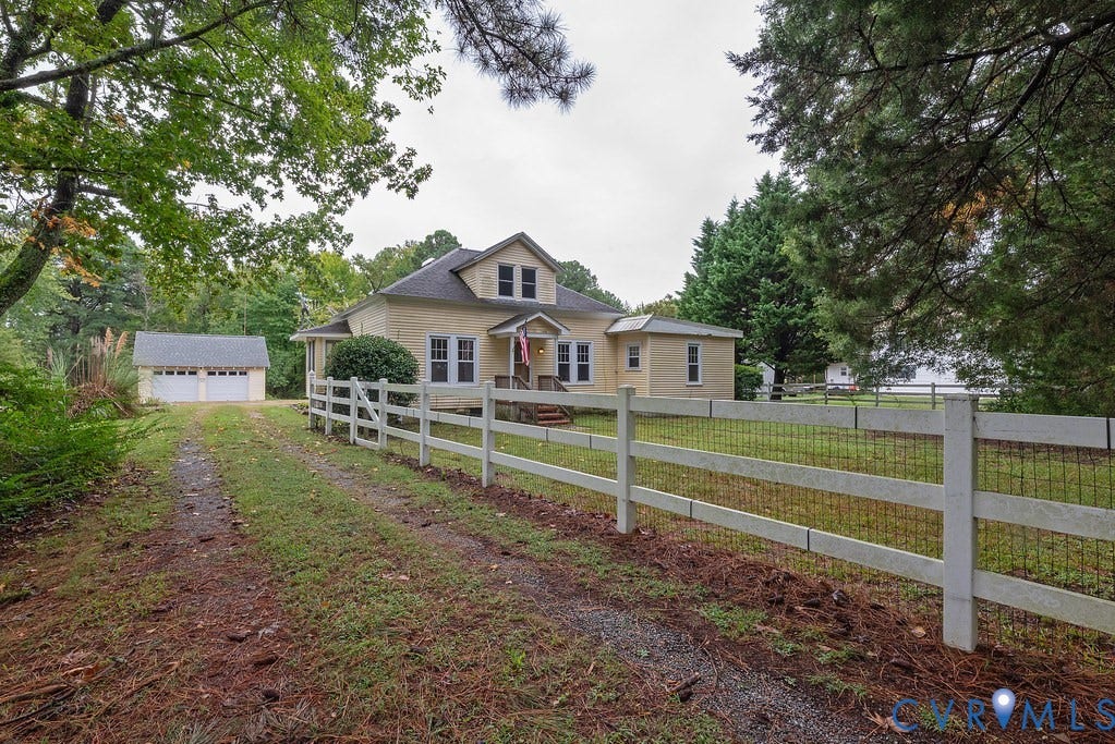 Two-story residence with a covered front porch, a detached two-car garage, and a white fence bordering the property