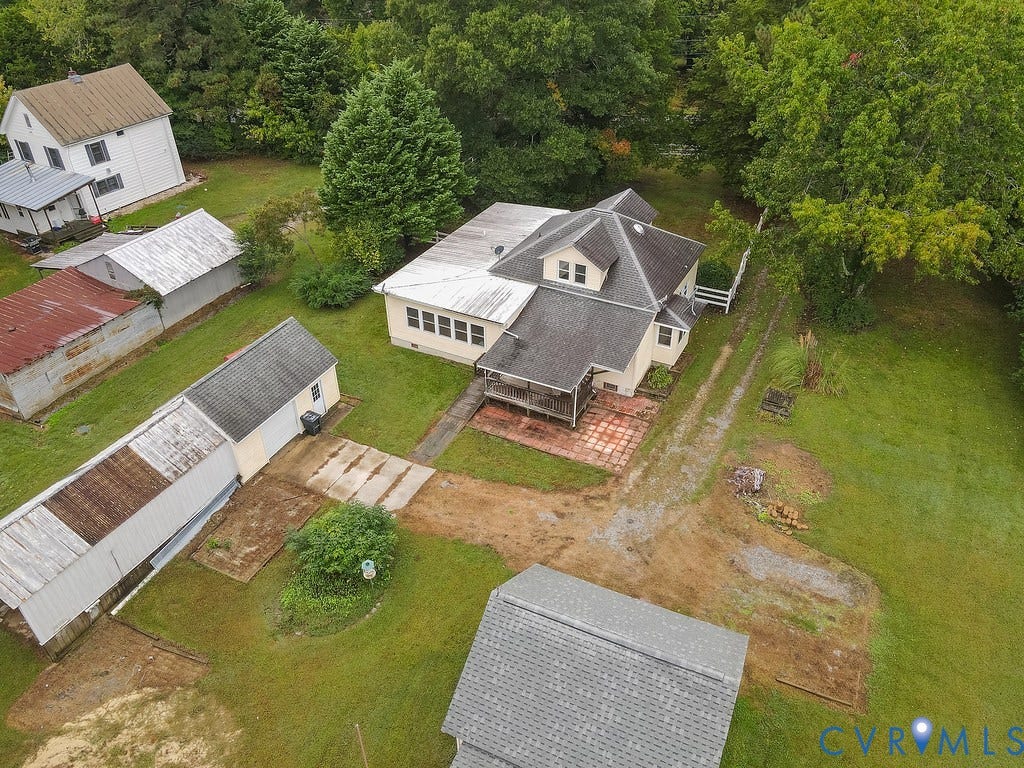 Expansive grounds featuring multiple outbuildings, mature trees, and a paved patio area
