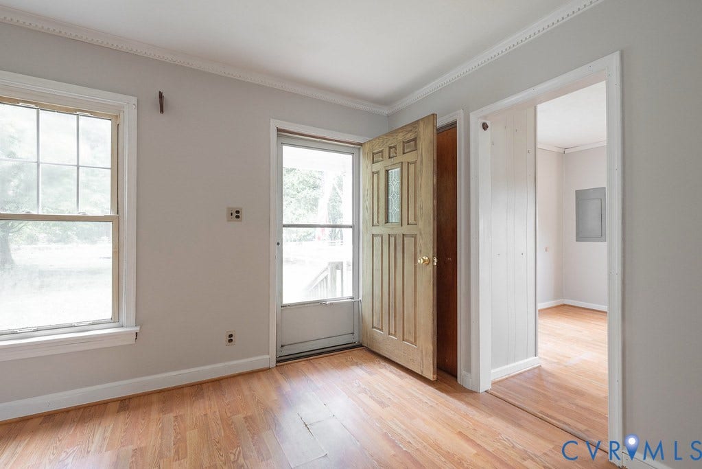 Wood-finish flooring, white trim, crown molding, and two windows