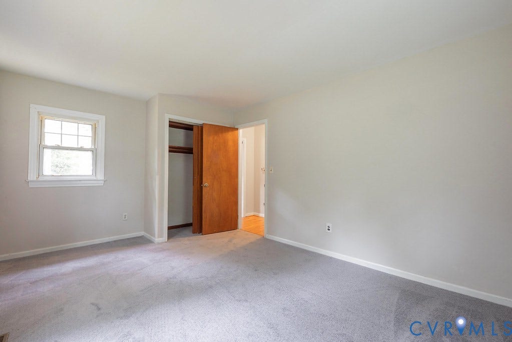Carpeted flooring, single pane window, wood-finish doors, and white painted walls