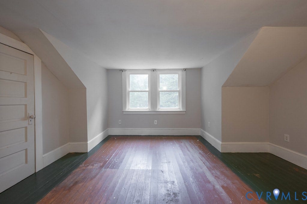 Hardwood flooring, painted walls, white trim, and a five-panel door with white hardware