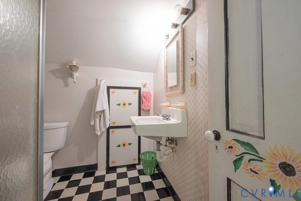 Checkered tile flooring, wall-mounted sink, wall-mounted mirror, overhead lighting fixture, built-in shelving
