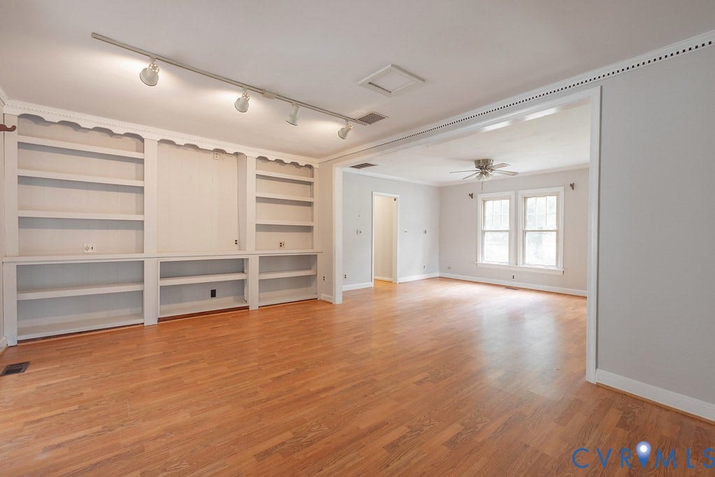 Wood-finish flooring throughout, built-in shelving, track lighting, ceiling fan, and crown molding