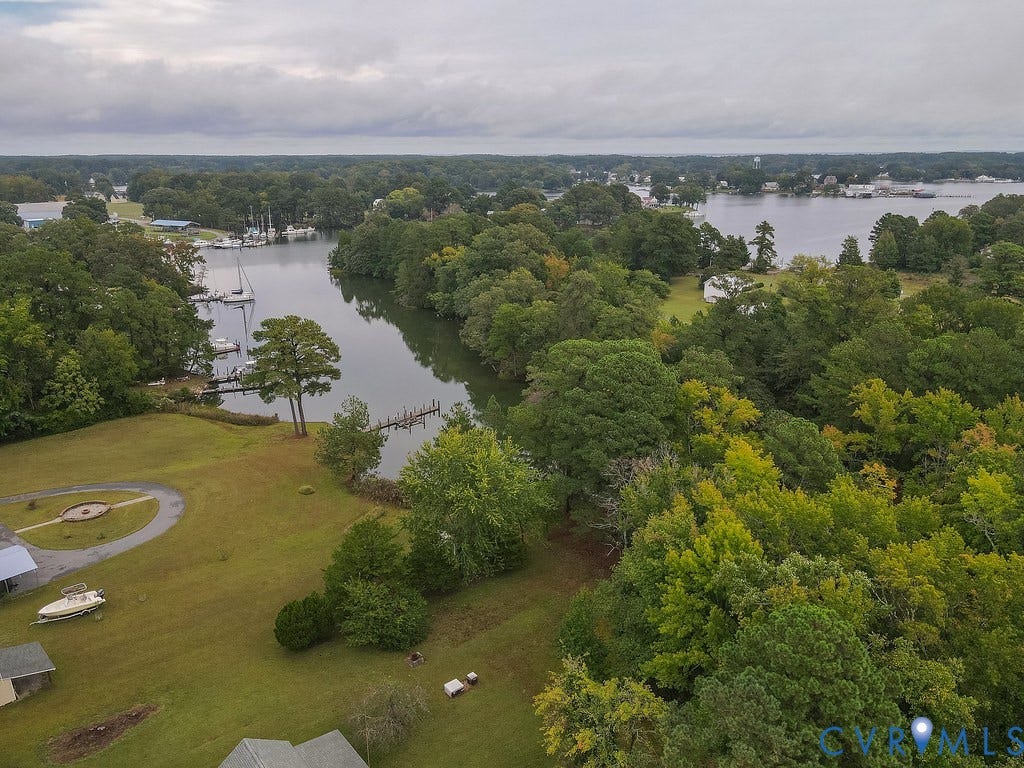 Waterfront property with private boat dock, surrounded by mature trees, and featuring a circular driveway