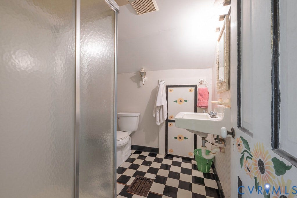 Frosted glass shower enclosure, checkerboard floor tiles, wall-mounted sink, and a mirrored medicine cabinet