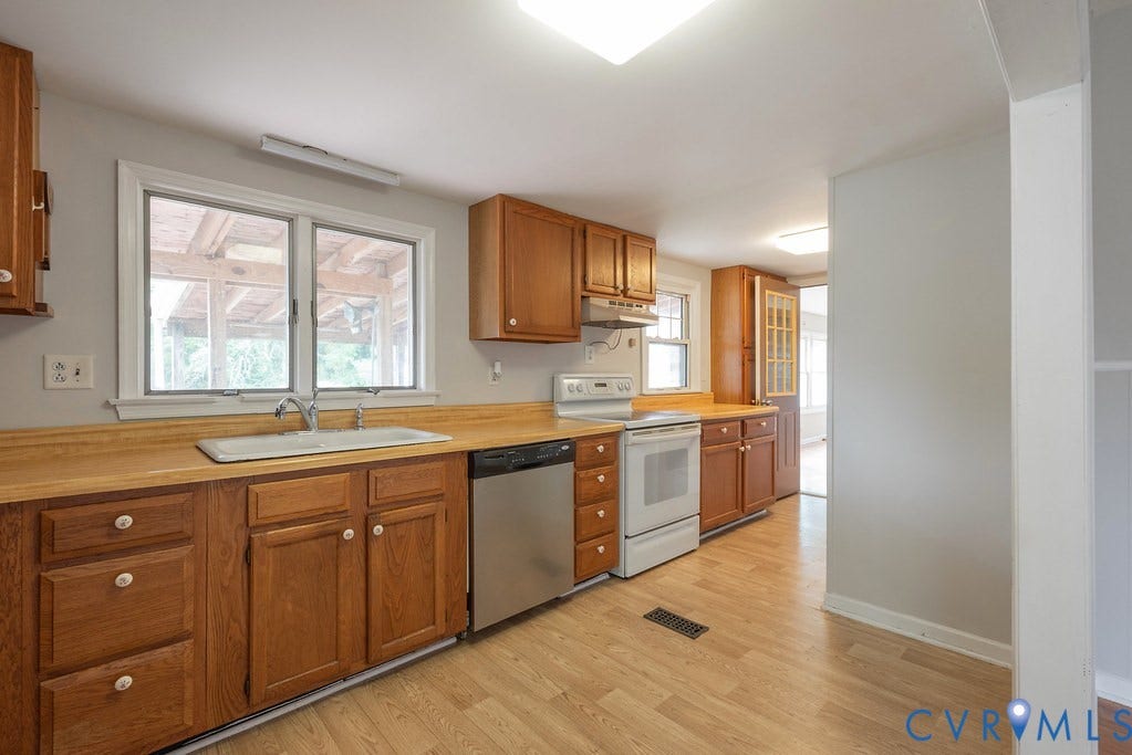 Kitchen with wood-finish flooring, wood cabinetry, laminate countertops, and stainless steel dishwasher