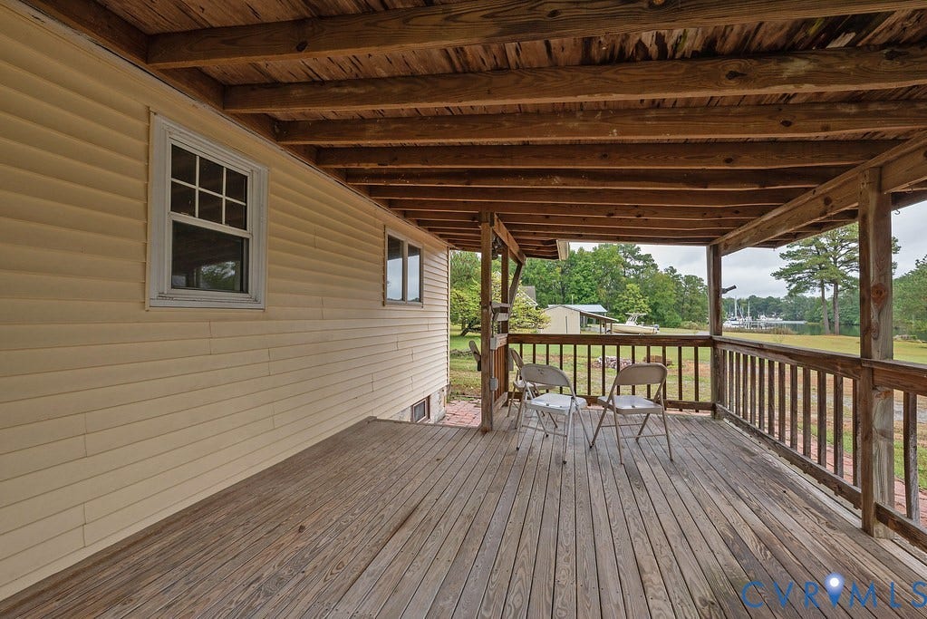 Expansive wooden deck with railing, featuring a natural wood ceiling and exterior siding