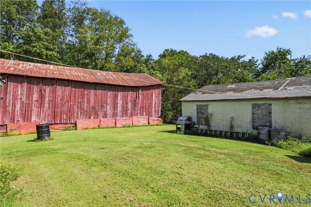 117 Gardners Road, Cross County Area, Mineral, VA 23117 Expansive grassy area featuring a large red barn with a corrugated metal roof and a separate light-colored structure with a shingle roof