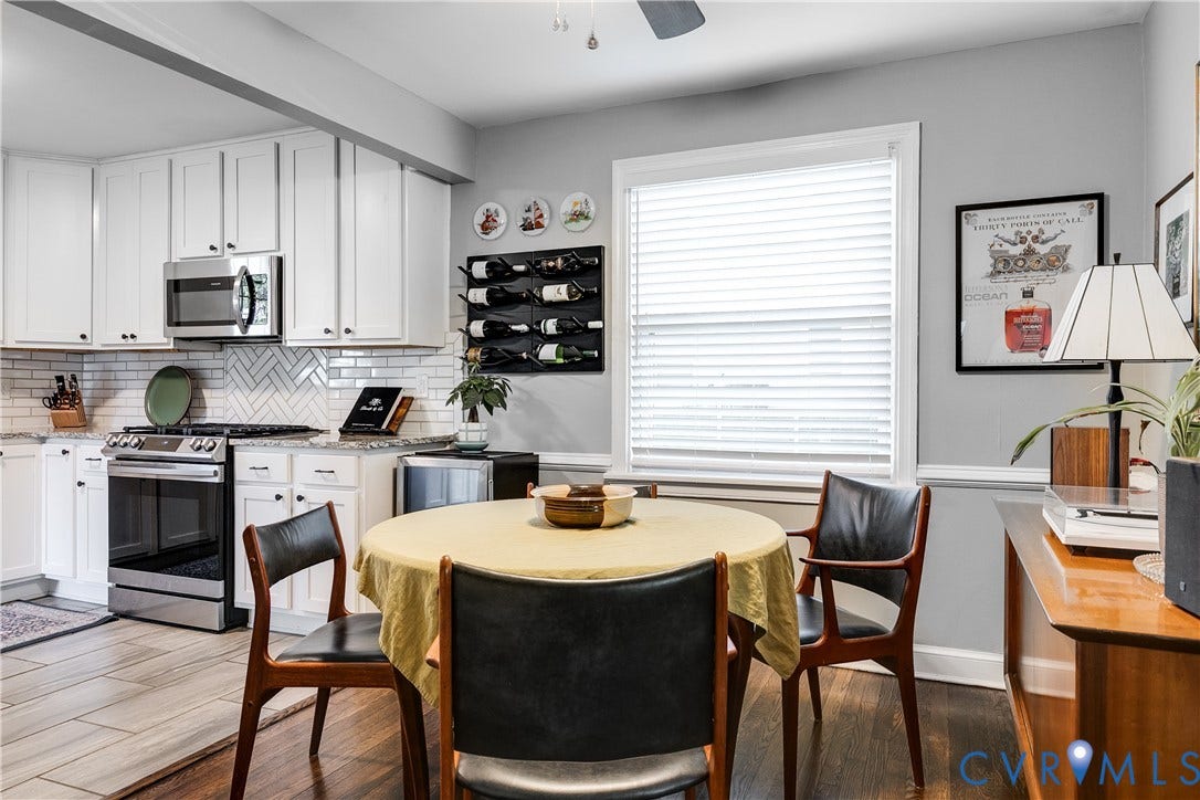 White cabinetry with black hardware, stainless steel appliances, herringbone tile backsplash, and light-toned wood-finish flooring
