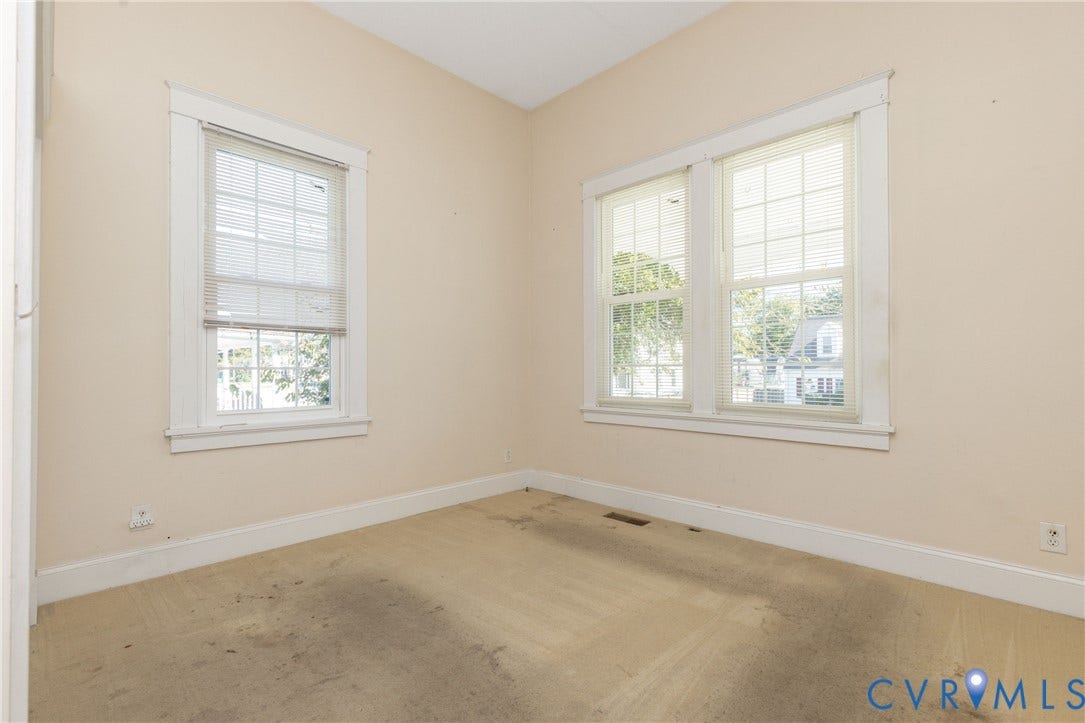 Hardwood floors under carpet. Neutral-toned interior space featuring multi-pane windows and traditional window casing