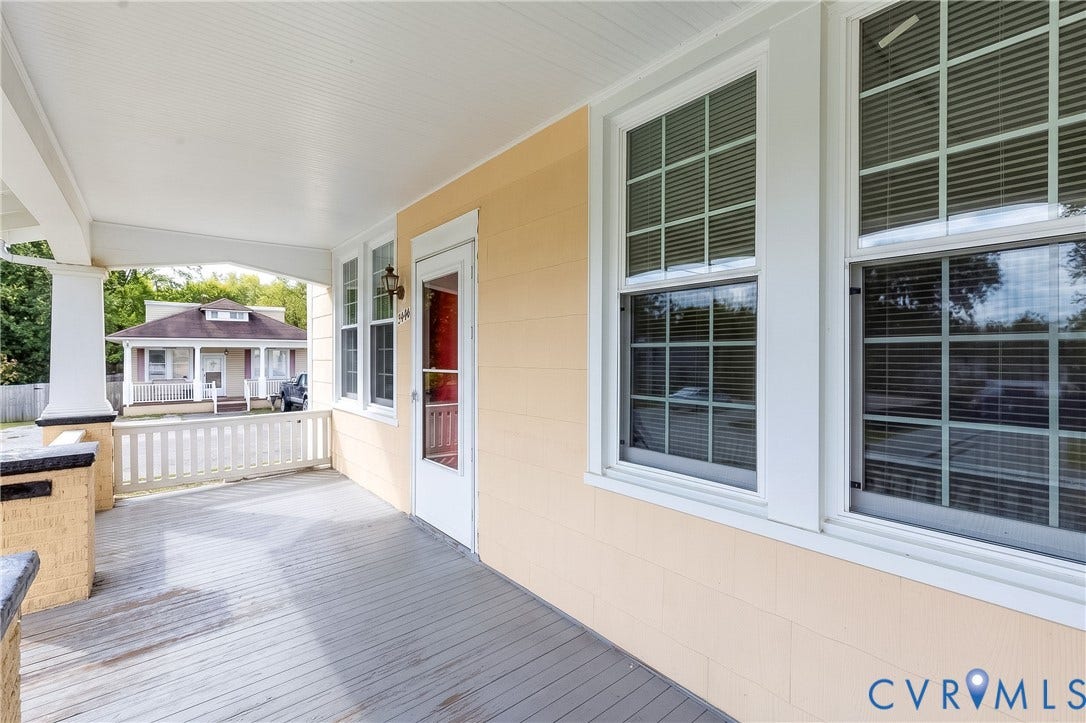 Covered front porch featuring wood-plank flooring, a beadboard ceiling, multi-pane windows, and a masonry column base