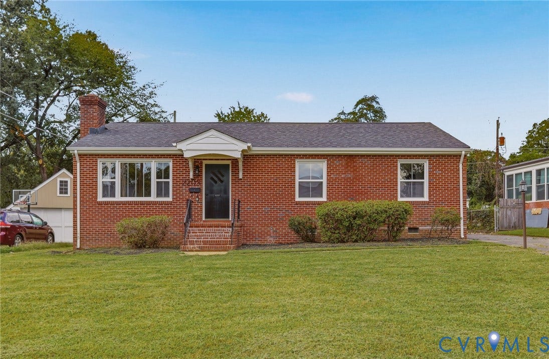Brick exterior featuring a gabled roof and white window trim