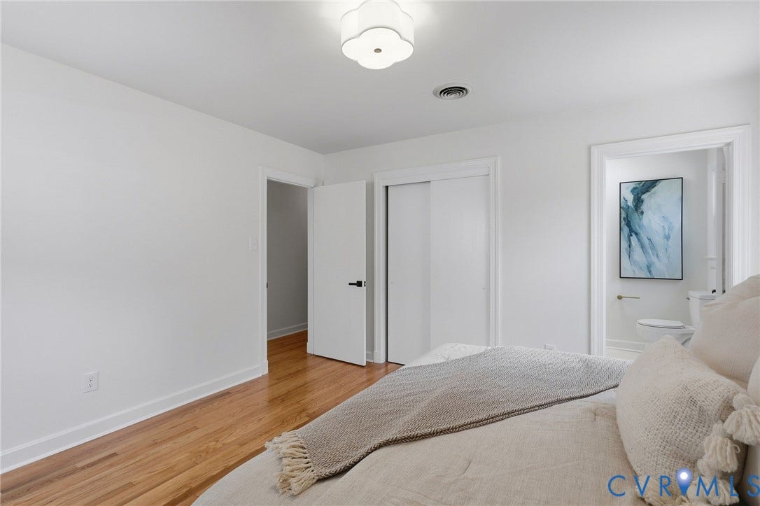 Hardwood flooring, white walls, flush mount ceiling light fixture, sliding closet doors, and solid core interior doors