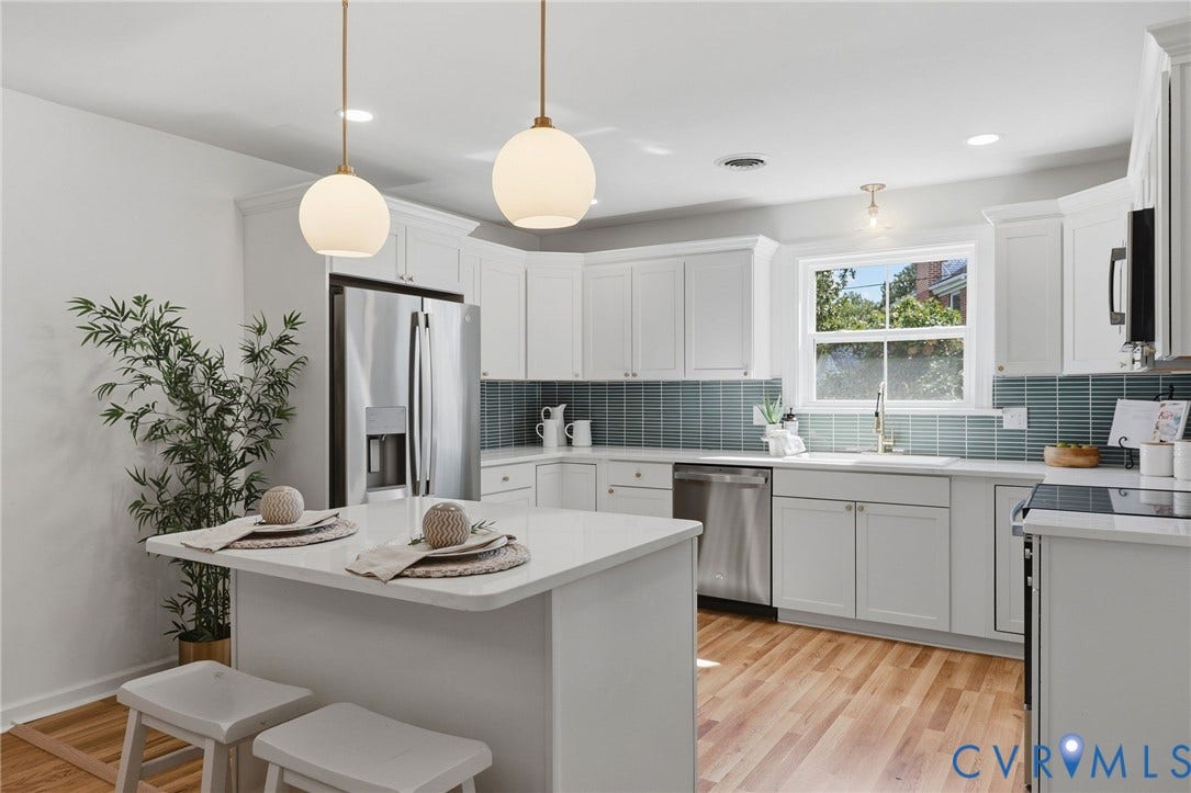 White cabinetry and a waterfall countertop island featuring two pendant lights