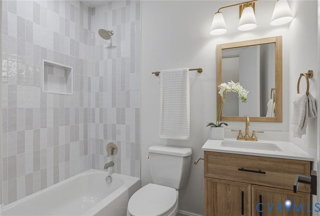 Bathtub with tiled surround, integrated shower niche, and brushed nickel fixtures